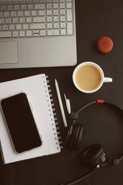 Telefon ekranı, kulaklıklar, dizüstü bilgisayarlar, bir fincan kahve, kurabiyeler. Serbest çalışmak, Webinar almak, uzaktan çalışmak, müzik dinlemek, çalışmak..