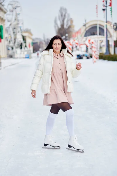 Brunette woman is skating outdoor. New Years holidays, good mood. Dreams come true concept.