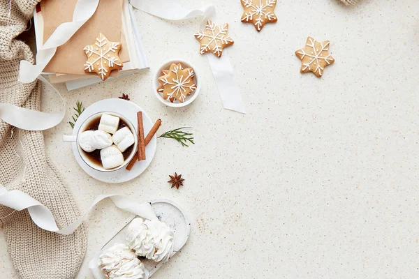 Christmas aesthetic seasonal background with cup of hot drink, white marshmallows, homemade snowflakes cookies, cinnamon sticks and books at cozy home. Copy space.