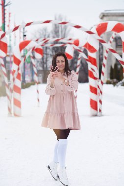 Neşeli mutlu genç kadın dışarıda buz patenlerinin üzerinde Noel karamel çubuğu tutuyor. Noel tatili, dışarıda eğlenmek..