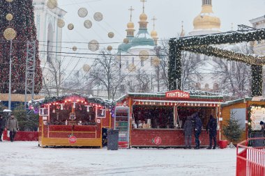 Kyiv, Ukrayna - Ocak 2022: Karlı bir günde Noel pazarı - tapınak, Noel ağacı, atlıkarınca, insanlar, dükkanlar ve süslemeler. Savaştan önce bayram.