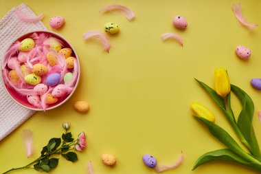 Renkli yumurtalı pembe kase, pembe tüyler, bahar çiçekleri. Mutlu Paskalya parlak geçmişi. Kopya alanı olan kartpostal.