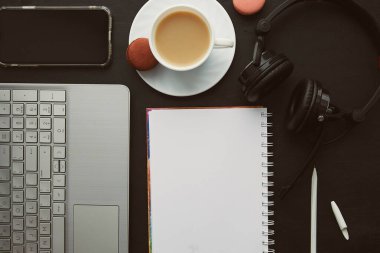 Not defteri ve telefon ekranı dizüstü bilgisayarlar, kulaklıklar, kahve fincanları ve badem kurabiyeleriyle modelleniyor. Serbest yaşam tarzı, webinar almak, uzaktan çalışmak, çalışmak, müzik dinlemek.