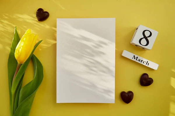 Feminine post card mock up with trendy shadows, chocolate hearts, text 8 of March with yellow tulip. Women\'s Day concept. Mockup postcard. Copy space.