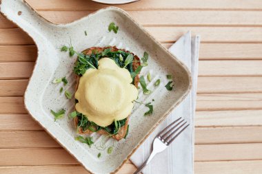 Vejetaryen yumurtaları, bitkisel soslu Benedict yemeği, tam tahıllı ekmek, füme tofu, taze soğan, yeşillik, bezelye filizi dışarıda.