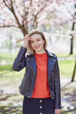 Happy smiling woman in spring park near pink sakura flower tree. Cottagecore aesthetics, sustainable. Connecting with nature, self-discovery