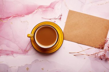 Mock up of envelope with cup of coffee, top view. Fluid art and gypsophila decorations flat lay. Morning concept