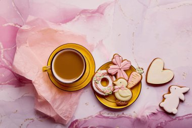 Aesthetics Easter pink background - pastel glazed cookies and coffee. Spring card with baked symbols of Easter, copy space.