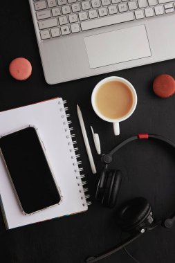 Mock up of phone screen, laptop, cup of coffee, macaroons and headphones. Freelance concept, taking webinar, working remotely, listening music, studying.