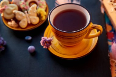 Aesthetic yellow tea cup and Easter homemade cookies with decorations. Holiday food, tea time.