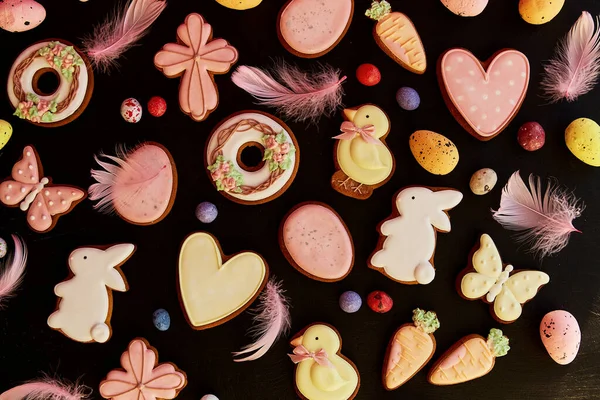Springtime Easter aesthetics glazed cookies decorated feathers on black background. Happy Easter banner.