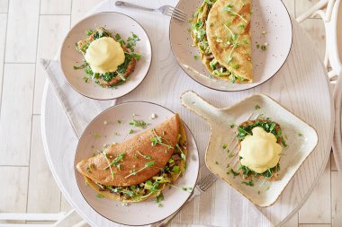 Vejetaryen sağlıklı kahvaltı. Bitkisel soslu yumurta, ekşi ekmek, tofu, taze soğan, yeşillik. Mantar, bezelye filizi ve avokado dolu krepler.