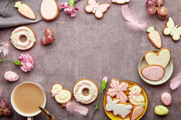 Easter aesthetic coffee time background. Glazed decorated cookies, coffee cup, feathers flat lay. Spring stylish background with copy space.