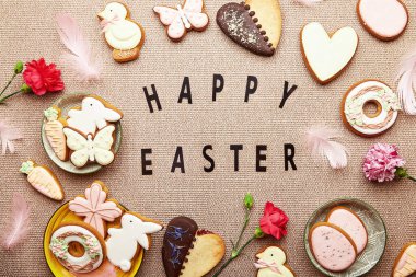 Yazılı Paskalya arkaplanınız kutlu olsun. Estetik Paskalya kurabiyeleri, pembe çiçekler ve yumurtalar düzdü.