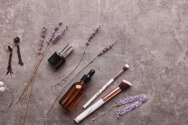 Aesthetic feminine flat lay with lavender, make up brushes, accessories, dropper bottle, nail polish. Feminine background with copy space.