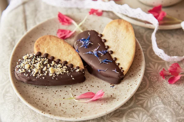 Vegan heart shaped cookies among flowers. Romantic holiday food background.