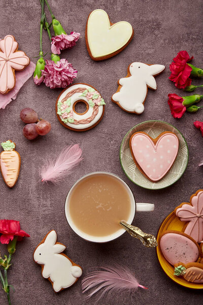 Stylish aesthetic Easter decorated cookies, coffee cup, feathers and aster flowers flat lay. Spring background