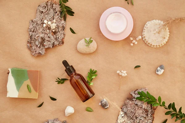 stock image Natural cosmetic products. Dropper serum glass bottle of hyaluronic acid, natural soap and mucin cream. among pebbles and tree bark