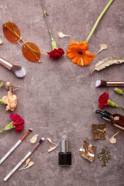 Makyaj fırçaları, aksesuarlar, damlayan şişeler, güneş gözlükleri, kozmetik ürünleri ve merkezinde fotokopi alanı olan Gerbera çiçekleri..