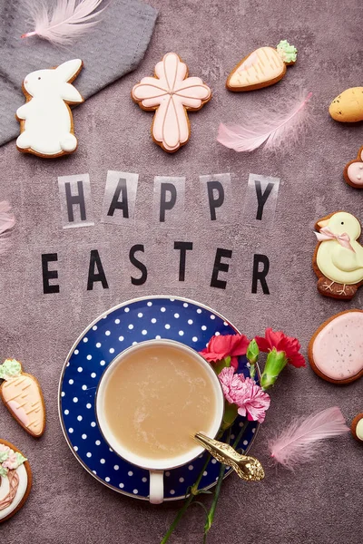 Aesthetic Easter background with text Happy Easter. Stylish decorated Easter cookies, pink flowers, coffee cup and eggs flat lay