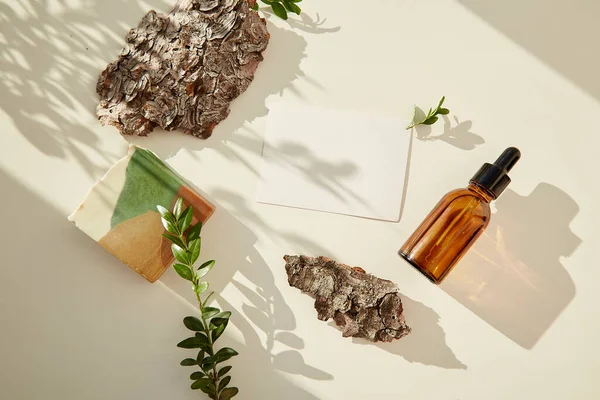 stock image Dropper serum glass bottle of hyaluronic acid, natural soap among pebbles and tree bark. Stationery card mockup. Copy space