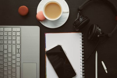 Klasik telefon ekranı, dizüstü bilgisayar, kulaklık ve kurabiyeli kahve modeli. Serbest yaşam tarzı, Webinar almak, uzaktan çalışmak, müzik dinlemek, çalışmak..