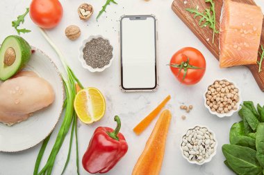 Fodmap, Akdeniz, Paleo diyet konsepti ve ekran mobil modeli. Sağlıklı düşük fodmap malzemeleri - sebzeler, meyveler, tavuk eti, somon, fındık, yeşiller.