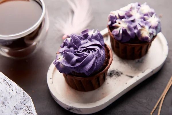 Purple aesthetics trendy floral cupcake and cup of coffee. French no sugar dessert close up.