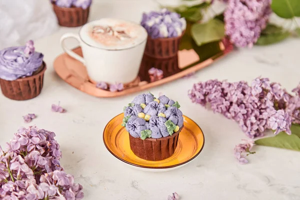 Floral purple cupcakes using trend Dreamy Escapism. Leisure and relax coffee time. Spring purple background. Beautiful food.