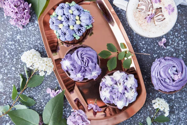 Floral purple cupcakes using trend Dreamy Escapism. Aesthetics desserts, coffee cup and lilac flowers background
