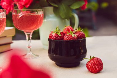Çilekli kase. Kırmızı ev yapımı cam, çilek karışımı, şarap. Güller buketi.