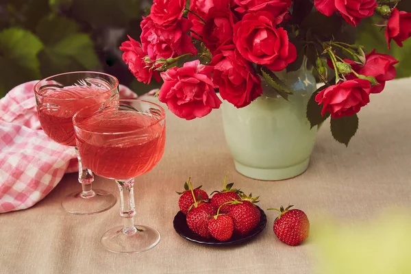 バラの屋外 イチゴとチョコレートと赤い輝くイチゴワインのカップルグラス 審美的な夏のテーブル設定 — ストック写真