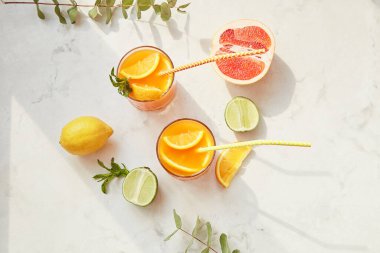 Turuncu yaz kokteylleri ve taze narenciye. Sert maden suyu, limonata, ferahlatıcı içecekler, düşük alkollü kokteyller, yaz partisi konsepti. Gölge ve güneş ışığı. Üst görünüm