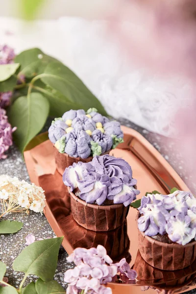 Purple aesthetics trendy floral cupcakes with flowers background. French no sugar dessert. Copy space.