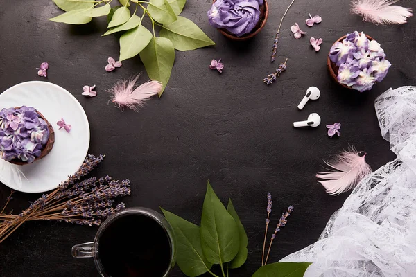 Purple aesthetics lifestyle background, trendy floral cupcake and cup of coffee, wireless headphones. Music, relaxation concept. Copy space in the center.