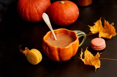 Balkabağı, badem kurabiyesi ve akçaağaç yaprakları arasında balkabağı şeklinde bir sonbahar kahvesi. Atmosferik rahat kahve zamanı..