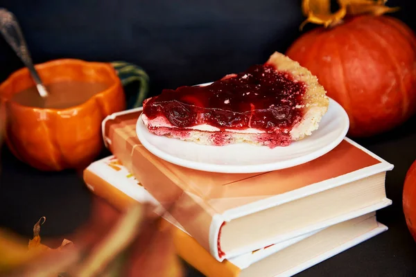 Aesthetics cozy home - autumn cup of coffee in shape of pumpkin, cherry pie and books. Atmospheric cozy coffee time.