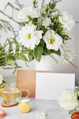 Kağıt zarflar ve kırtasiye kağıtları. Selamlar, davetiyeler, beyaz çiçeklerin, kurabiyelerin ve çayın arasındaki mesajlar için. Estetik masa ayarları, rahat bir ev. Boşluğu kopyala