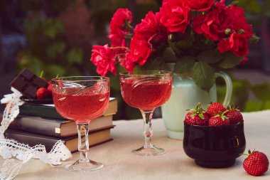 Birkaç kadeh kırmızı ev yapımı şarap. Doğal çilek karışımı ya da çalılık. Gül buketi. Estetik yaz masası.