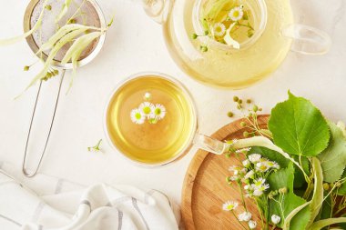 Doğal organik ıhlamur ve papatya çayı çiçekli çaydanlık ve fincan. Yaz sofrası kurma, doğal sağlıklı içecek, sosyal yardım ve emlak kavramı.