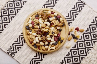 Estetik ahşap kase, çeşitli fındıklar, kuru üzümler ve kızılcıklar yukarıdan geliyor. Sağlıklı yiyecek ve atıştırmalıklar. Ceviz, badem, fındık ve fındık..