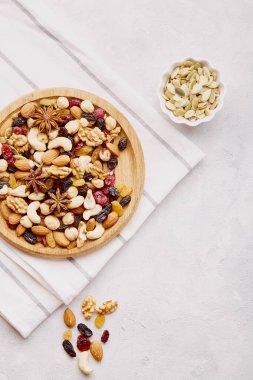 Estetik ahşap kase ve yukarıdan karışık fındık. Sağlıklı yiyecek ve atıştırmalıklar. Ceviz, badem, fındık ve kaju. Üzüm ve kızılcık üst görünüm.