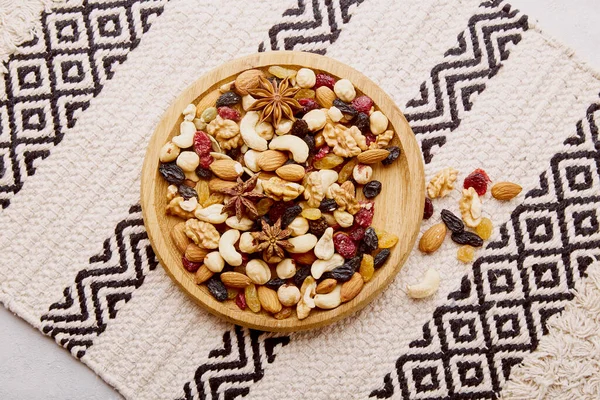 Estetik ahşap kase, çeşitli fındıklar, kuru üzümler ve kızılcıklar yukarıdan geliyor. Sağlıklı yiyecek ve atıştırmalıklar. Ceviz, badem, fındık ve fındık..
