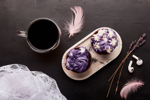 Purple aesthetics trendy floral cupcake and cup of coffee near wireless headphones. French no sugar dessert. Music, relaxation concept.