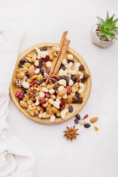 Healthy food and snacks. Aesthetic wooden bowl with assorted nuts, raisins and cranberries. Walnuts, almonds, hazelnuts, star anise and cashews.
