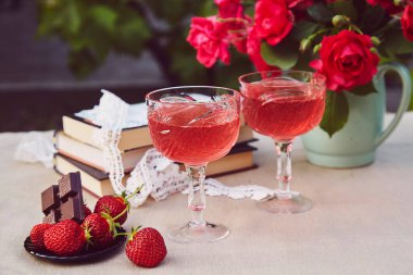 Kırmızı ev yapımı şarap. Doğal çilek karışımı ya da çalılık. Çilek ve çikolata. Gül buketi. Estetik yaz masa ayarları.