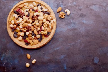 Estetik ahşap kase, çeşitli fındıklar, kuru üzümler ve kırsal arka planda kızılcıklar. Fındık, ceviz, badem, kaju, yıldız anason. Sağlıklı atıştırmalıklar ve tatlılar. Boşluğu kopyala.