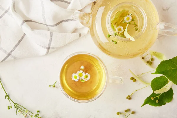 Tea brewing, tea ceremony, cup and teapot of freshly brewed herbal natural tea flat lay. Chamomile and linden healthy beverage. Cozy home concept.