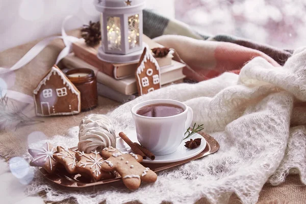 Cozy winter morning at snowy day. Aesthetic windowsill. Atmospheric warm home with books, gingerbread cookies, marshmallow, cup of coffee background.