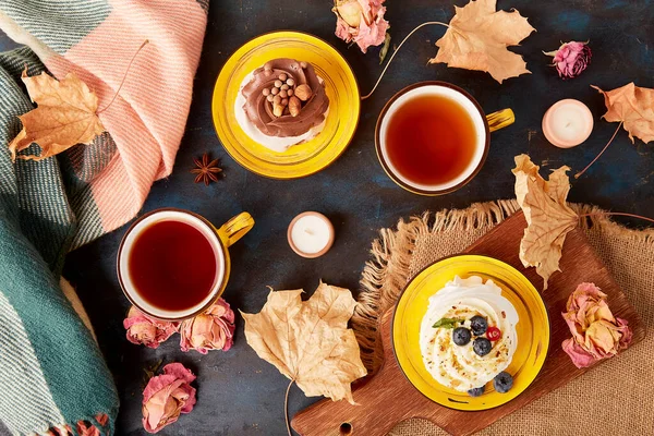 Aesthetic Pavlova cakes, Tea Cups. Autumn aesthetics tea time vibes among dry roses, leaves. Autumn teble setting.